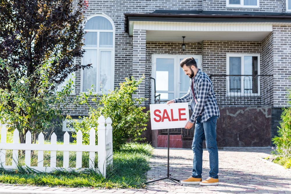 Young,Man,With,Sale,Board,Selling,His,House